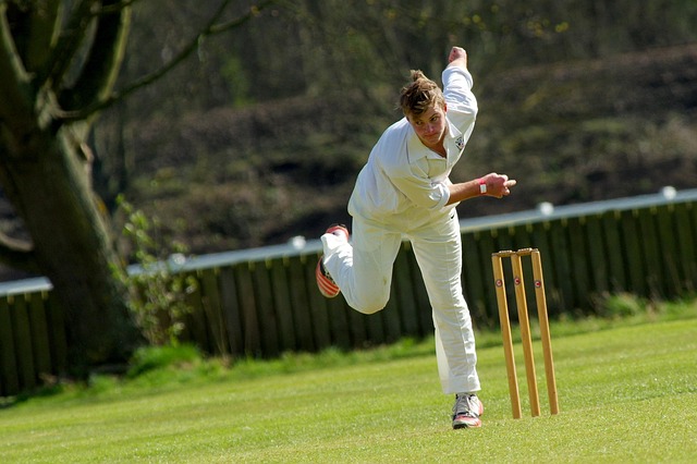 Coach demonstrating correct bowling technique to a player, refining skills.